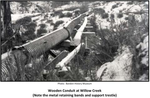 Photo: Bandon History Museum Wooden Conduit at Willow Creek (Note the metal retaining bands and support trestle)